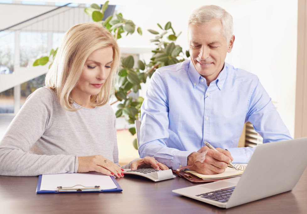 Shot of an older couple sitting at home in front of laptop and manage their monthly budget.